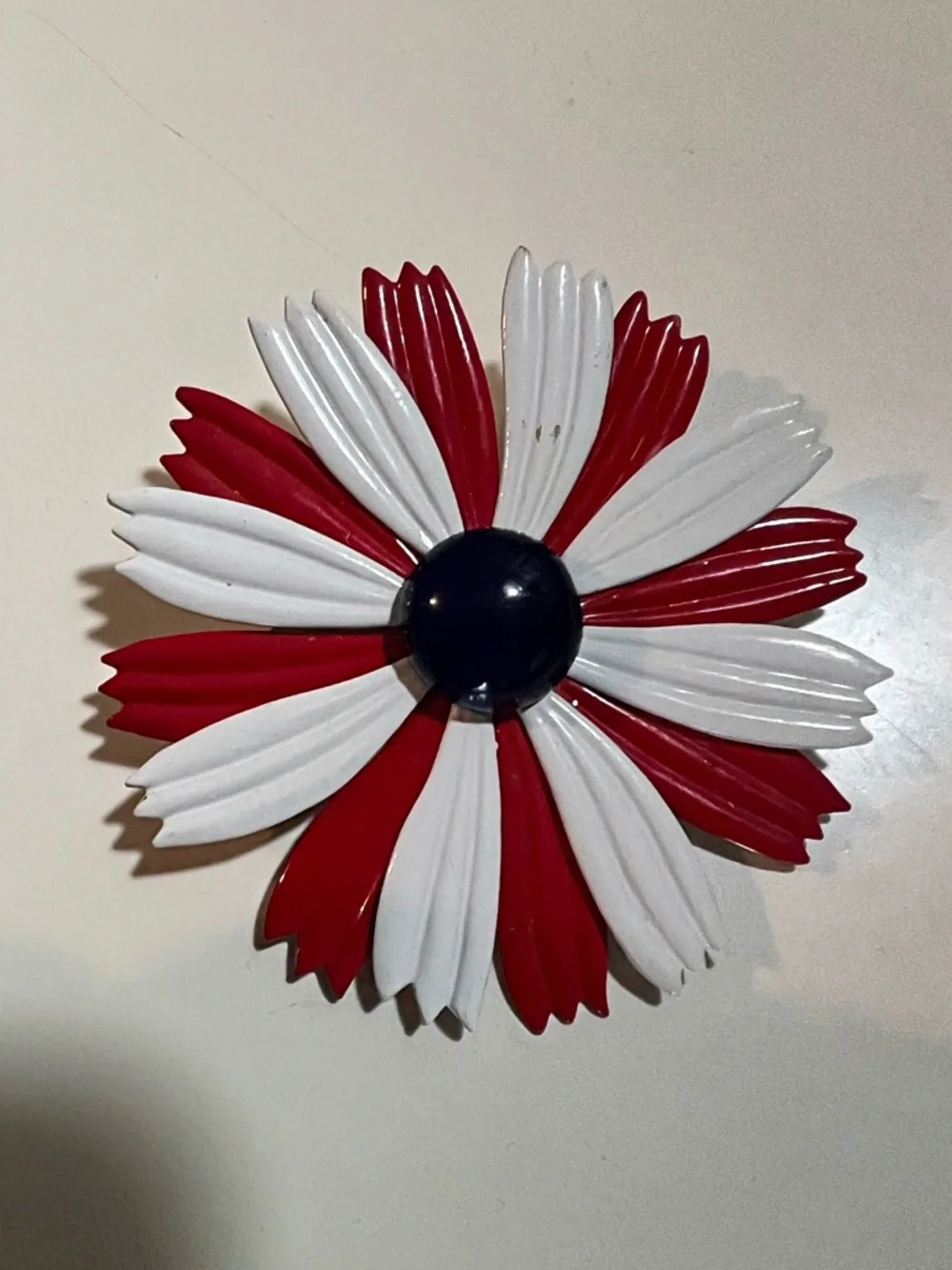 1960s enamel brooch with red and white petals and blue dome center.